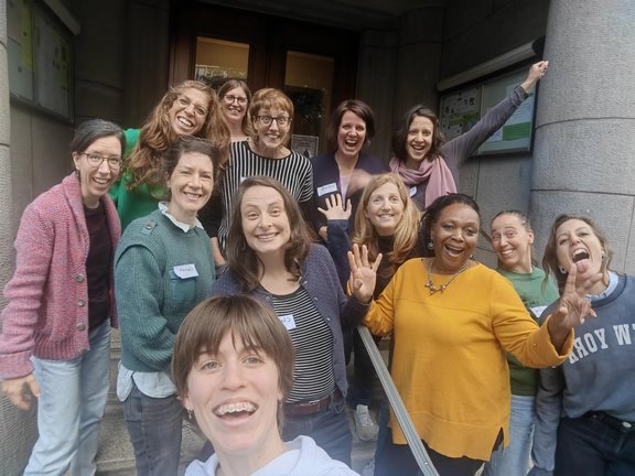 Gruppe fröhlicher Frauen posiert vor einem Gebäude